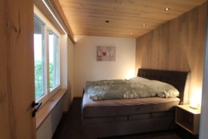 Gemütliches Schlafzimmer mit Holzdekor, großem Bett und natürlichem Licht.