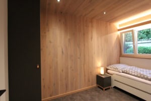 Modernes Schlafzimmer mit Holzpaneelen und großem Fenster.