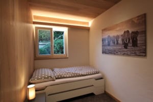 Kleines Schlafzimmer mit Bett, Fenster und Elefantenbild.