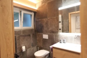 Zeitgenössisches Badezimmer mit dunklen Fliesen und Fenster.