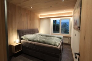 Gemütliches Schlafzimmer mit Doppelbett und Holzdekor-Wänden.