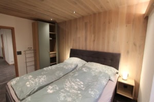 Gemütliches Schlafzimmer mit Doppelbett und Holzpaneel-Wand.