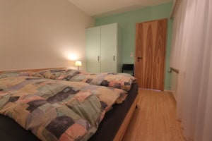 Gemütliches Schlafzimmer mit Doppelbett, Kleiderschrank und Nachttisch.