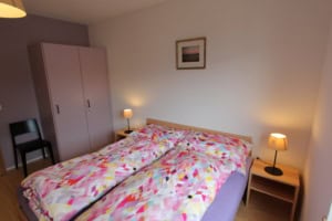 Gemütliches Schlafzimmer mit Doppelbett, Nachttischen und Beleuchtung.