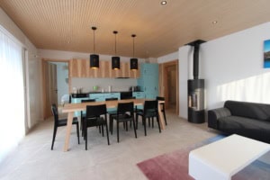 Helle, moderne Wohnküche mit Esstisch, Kamin und Blick ins Wohnzimmer.