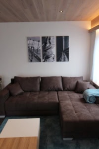 Gemütliches Wohnzimmer mit braunem Sofa und Segelboot-Wandkunst.