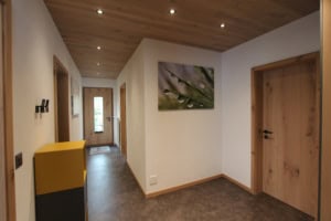 Heller Flur mit Holzdecke und Wandbild mit Wassertropfen.
