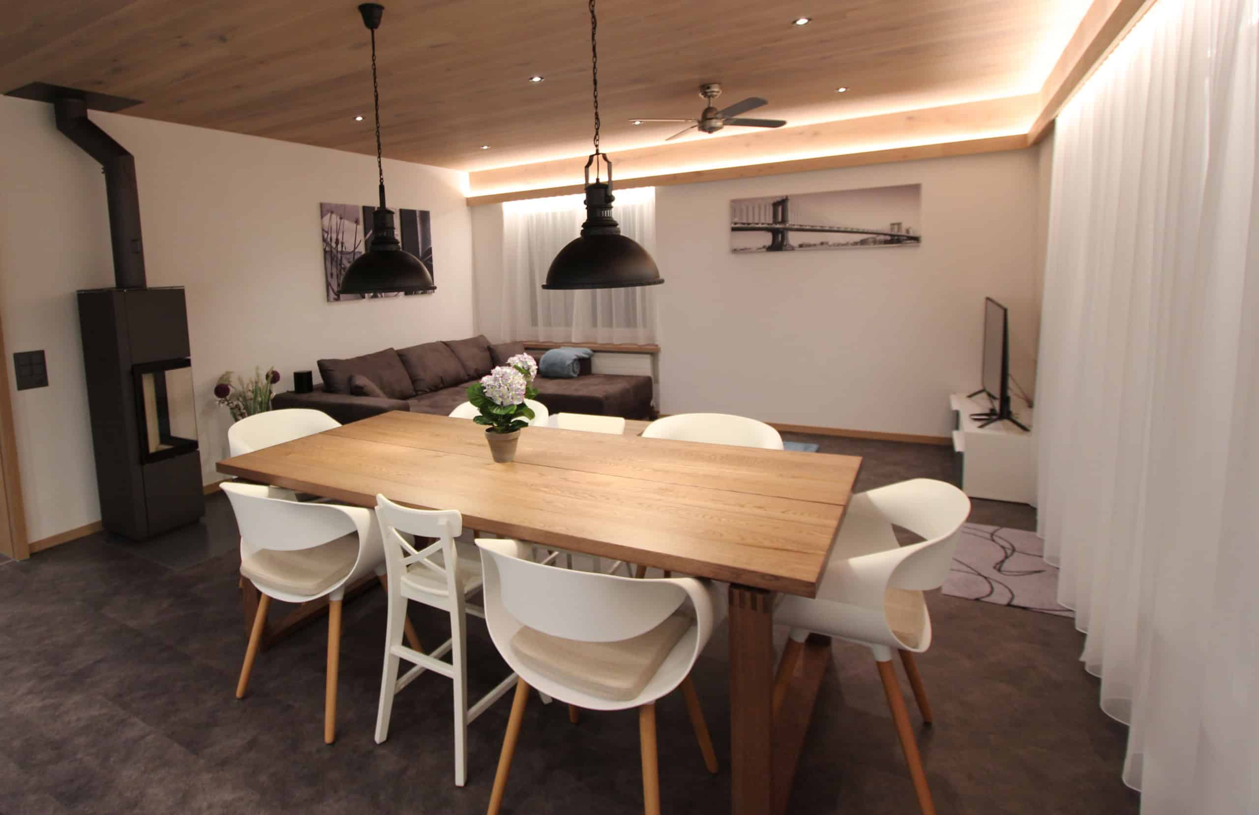 Gemütliches Esszimmer mit Holzdecke, Kamin und moderner Einrichtung.