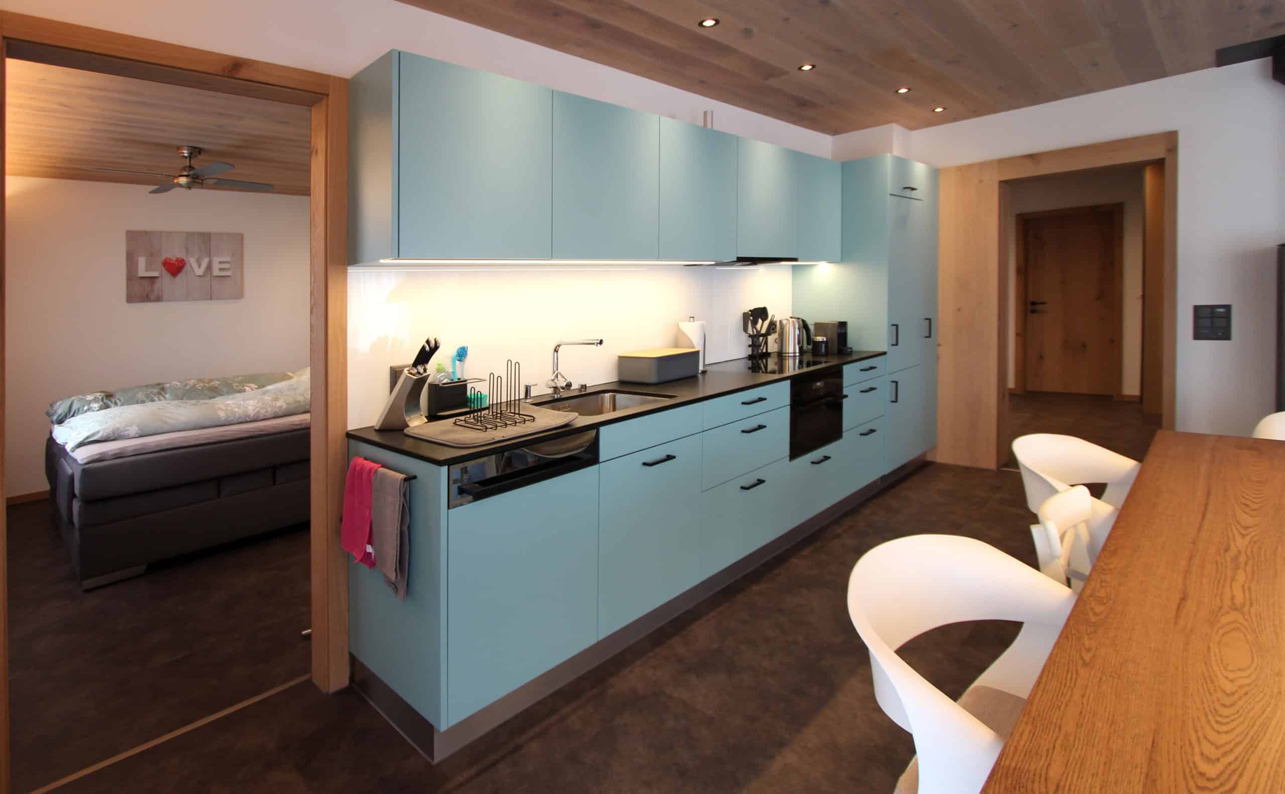 Helle moderne Küche mit blauen Schränken und Küchenutensilien.