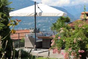 Terrasse mit Sitzbereich, Sonnenschirm und Blick auf Berge.